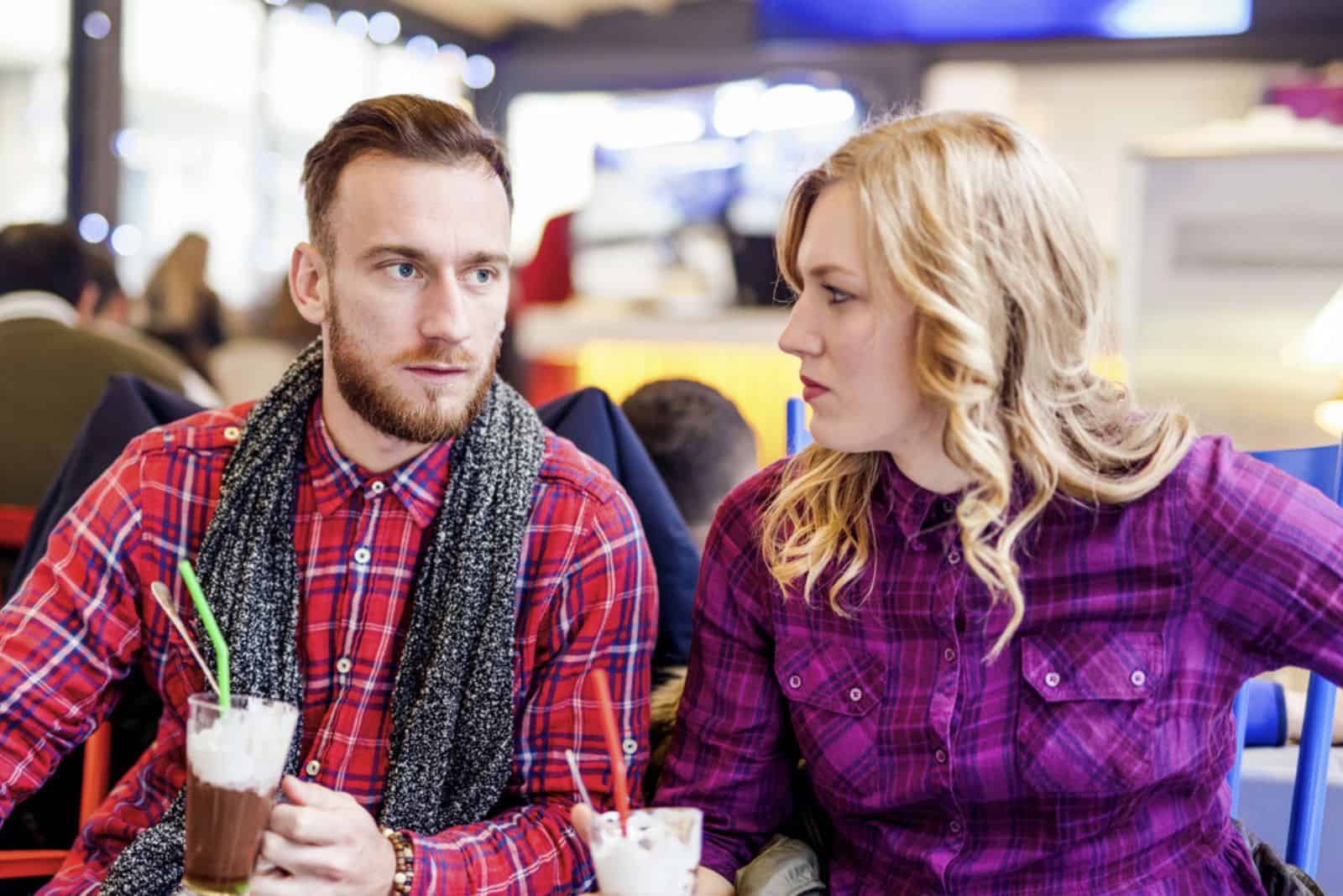 Eine Frau mit blonden Haaren sitzt neben einem Mann und sie unterhalten sich