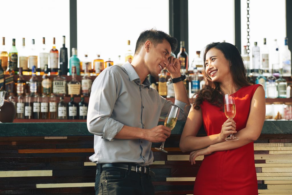Eine Frau und ein Mann flirten an der Bar mit Wein