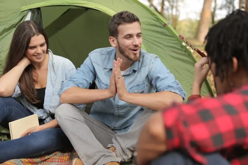 Eine Gruppe von Freunden sitzt vor dem Zelt und redet