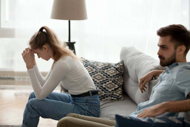 Müde unglückliche Paar sitzen getrennt auf der Couch und sprechen nicht ignorieren Entschuldigung nach dem Kampf zu Hause