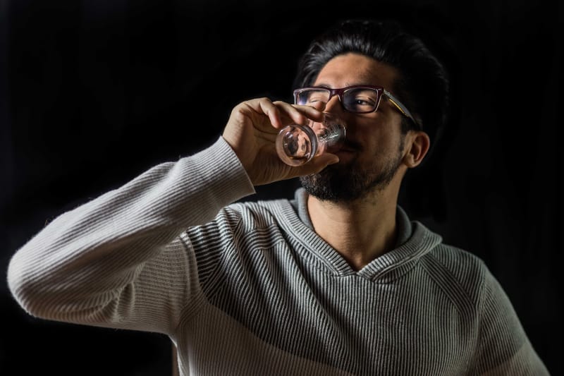 Mann trinkt auf klarem Trinkglas
