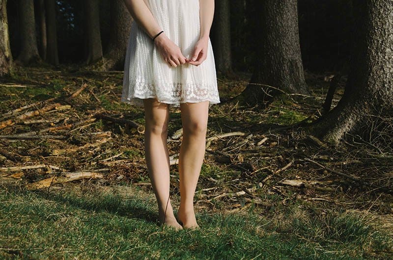 ein barfußes Mädchen in einem weißen Kleid in der Natur