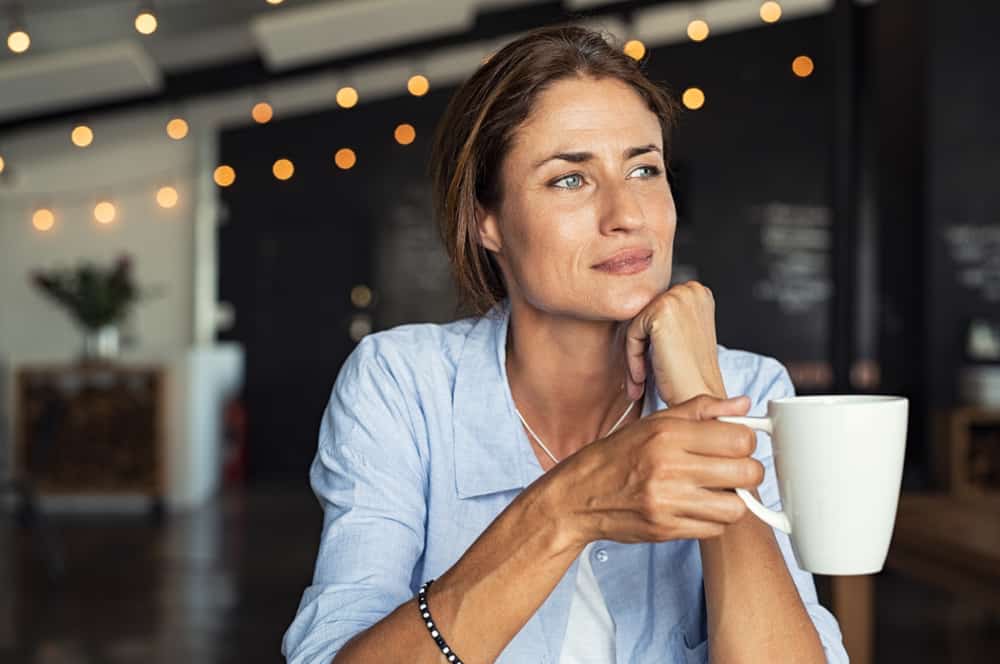 eine zutiefst nachdenkliche Frau, die eine Tasse Kaffee hält