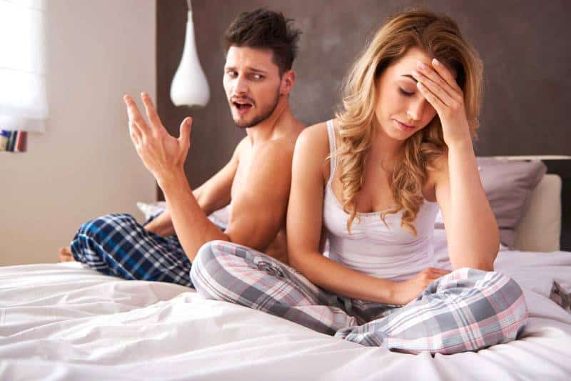 verärgerter Mann, der mit Frau im Schlafzimmer spricht