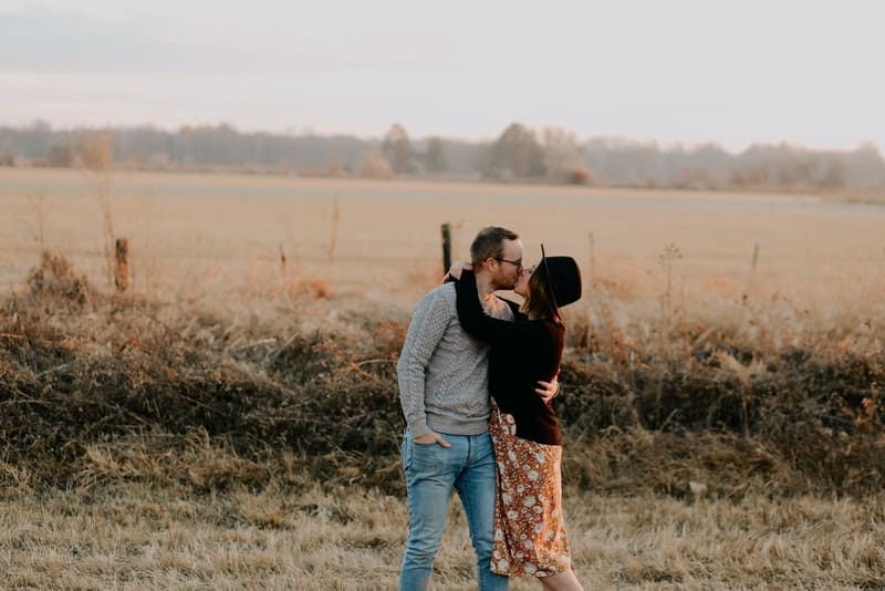 Ein Mann und eine Frau stehen im Gras und küssen sich