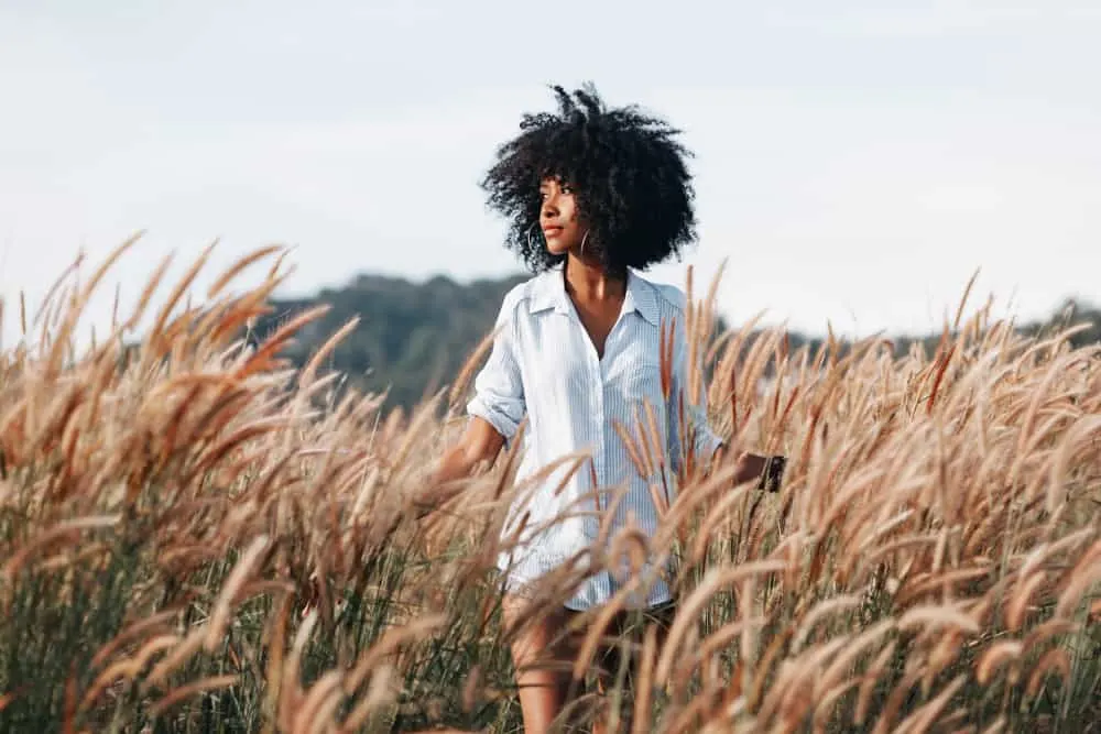 Eine afroamerikanische Frau im Hemd eines Mannes geht durch den Weizen
