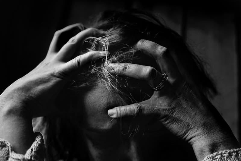Eine depressive Frau hält hysterisch den Kopf gesenkt