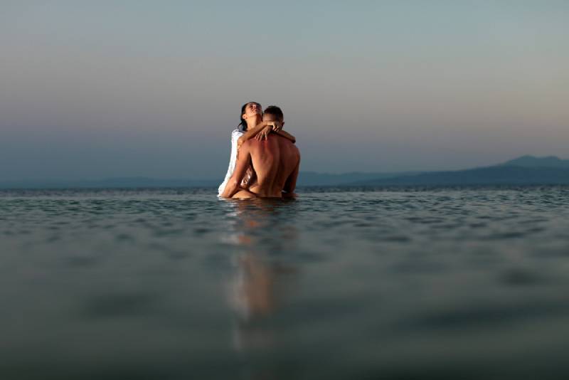 Zwei junge erwachsene Liebhaber, die in Wasserbeschaffenheit gegen Horizontstrand stehen