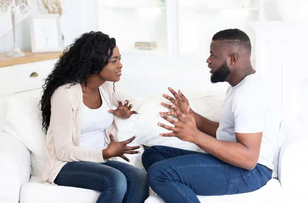 ein afroamerikanisches Paar, das auf der Couch sitzt und streitet