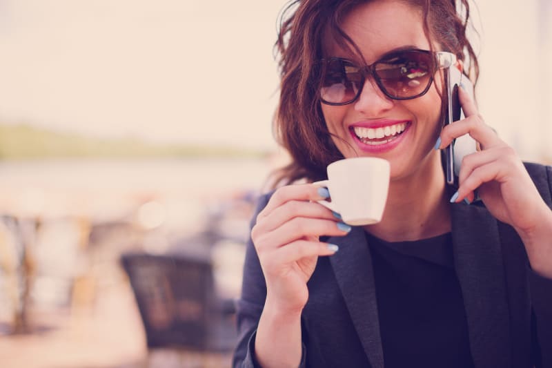 eine Frau telefoniert und trinkt Kaffee
