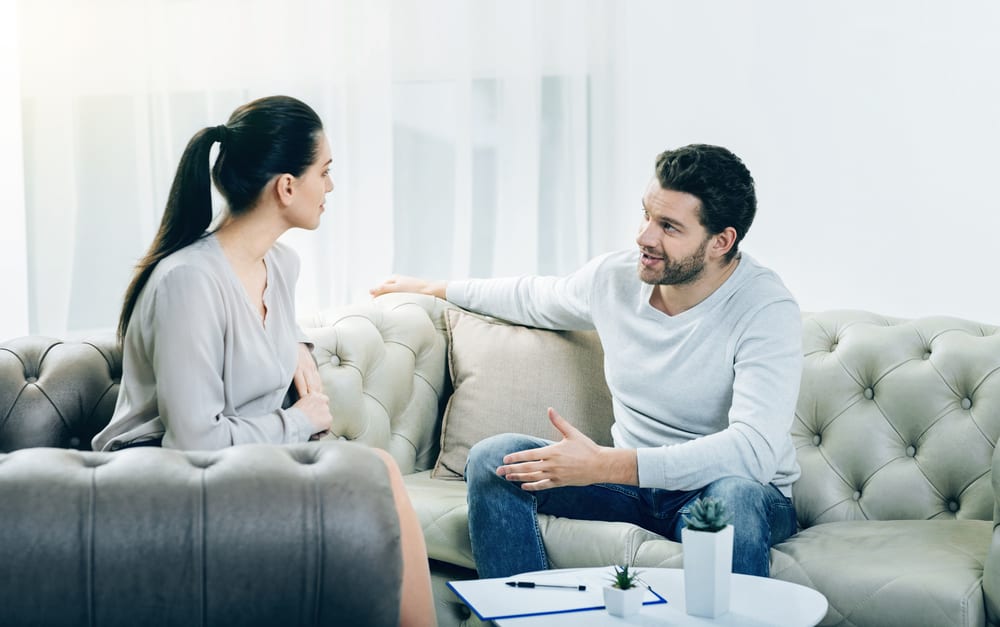 Der Mann überzeugt die Frau von etwas, als sie auf der Couch sitzen