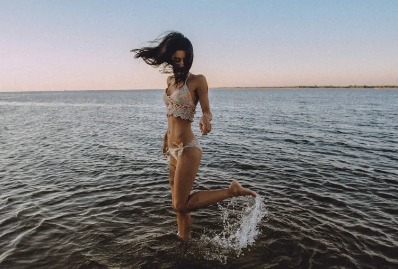 ein Mädchen im Bikini, das im Flachwasser spazieren geht