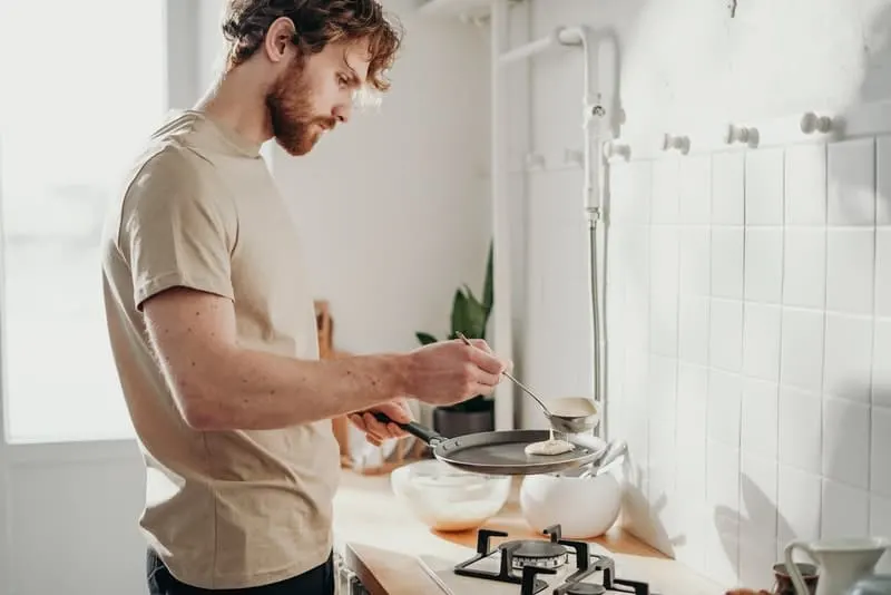 Ein Mann mit Bart bereitet Pfannkuchen zu