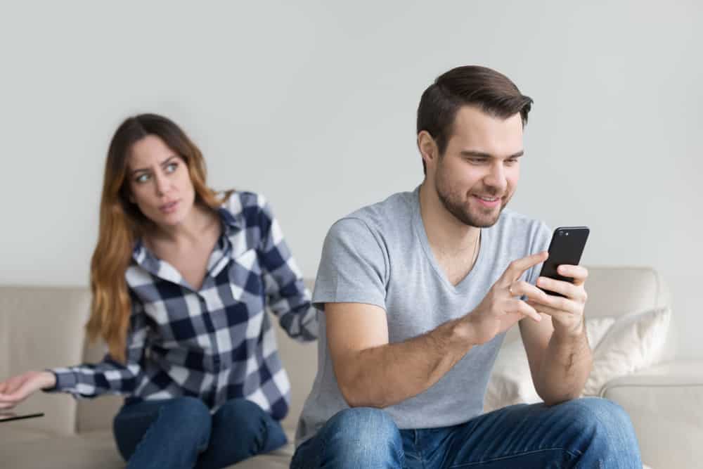 Ein Mann mit einem Handy in der Hand ignoriert eine verärgerte Frau