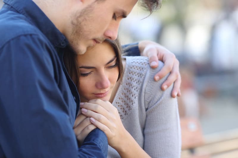 Ein Mann umarmt ein trauriges Mädchen