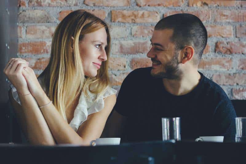 Ein junger Mann und eine junge Frau, die während eines Dates flirten. Paar sitzt im Cafe