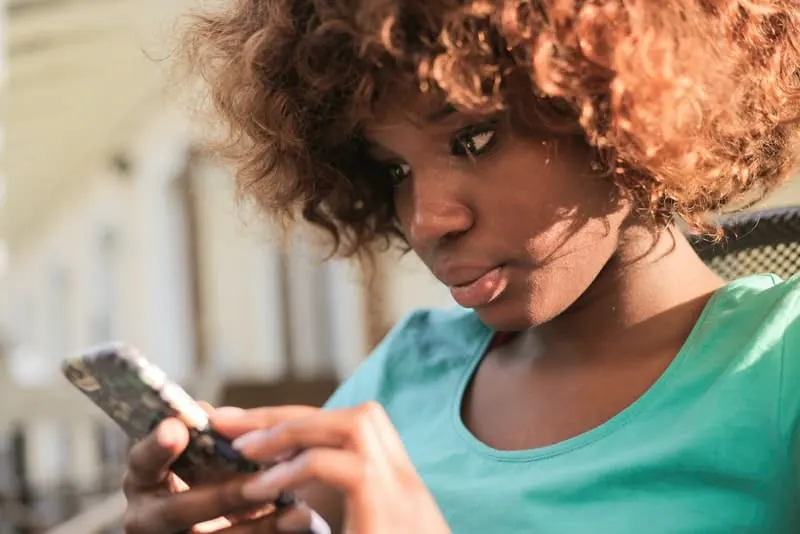 Eine besorgte schwarze Frau schaut auf ihr Handy