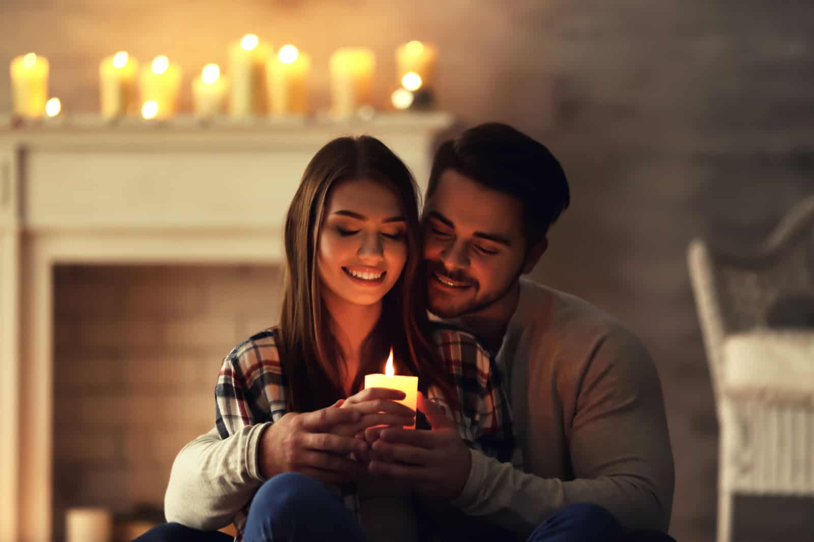 Glückliches junges Paar mit brennender Kerze zu Hause