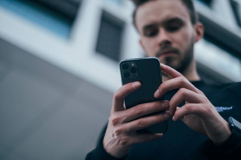 Mann schaut auf Telefon draußen