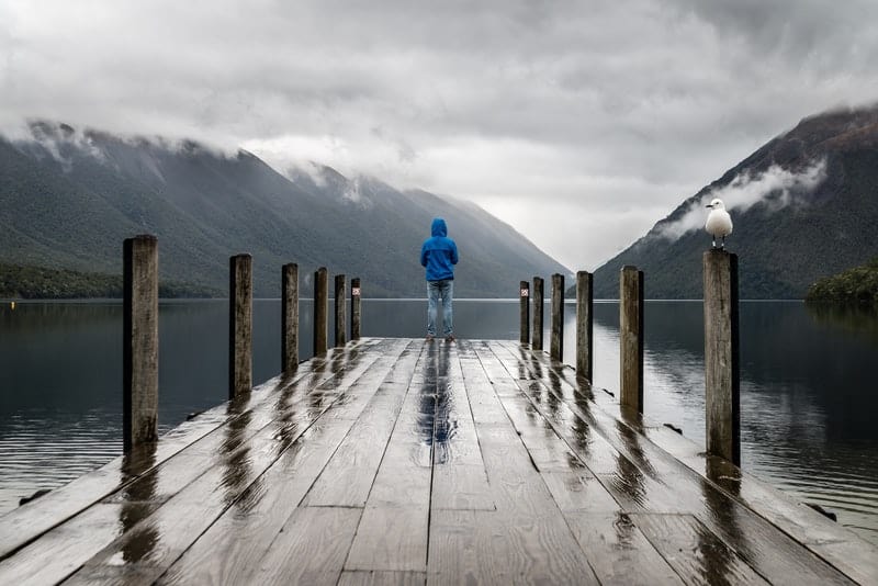 Ein Mann in blauer Jacke steht auf einem Piersee