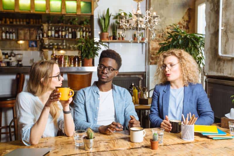 Zwei Frauen, ein Mann, der im Café spricht