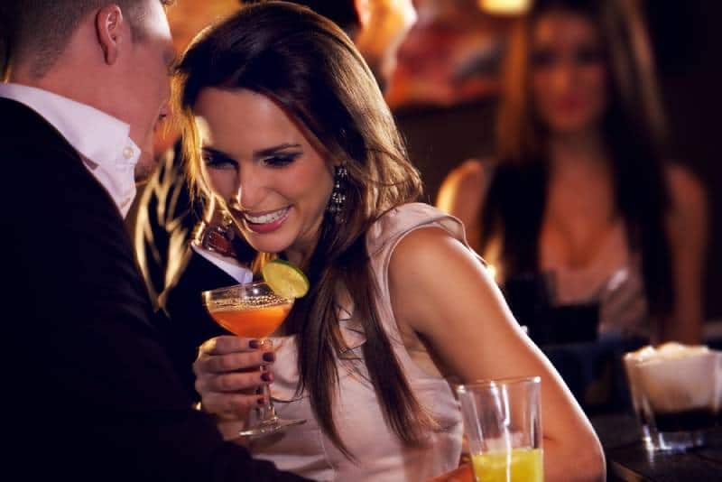 lächelndes Paar an der Bar genießt die Cocktailparty