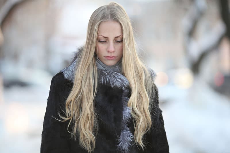 traurige blonde Frau mit langen blonden Haaren zu Fuß