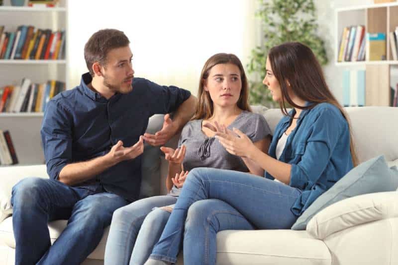 Drei ernsthafte Freunde sprechen auf einer Couch im Wohnzimmer zu Hause sitzend