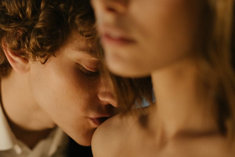 Ein Mann küsst leidenschaftlich die Schulter seiner desinteressierten Frau