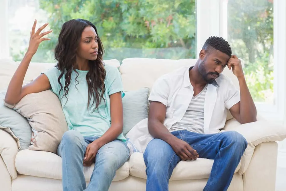 Eine schwarze Frau streitet mit ihrem schwarzen Mann auf der Couch