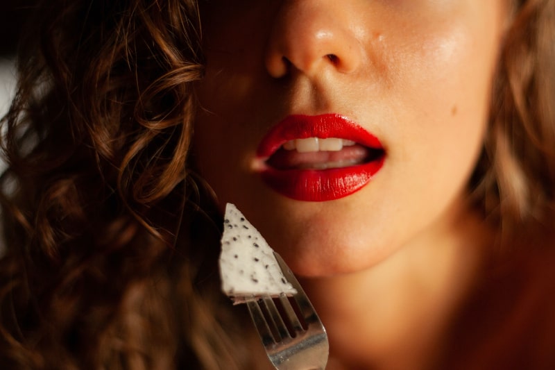 Frau mit rotem Lippenstift, der weiße und schwarze Sternverzierung hält