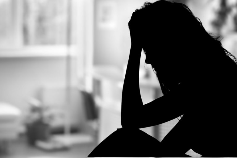 Silhouette einer Frau, die sitzt und ihren Kopf mit ihrer Hand hält