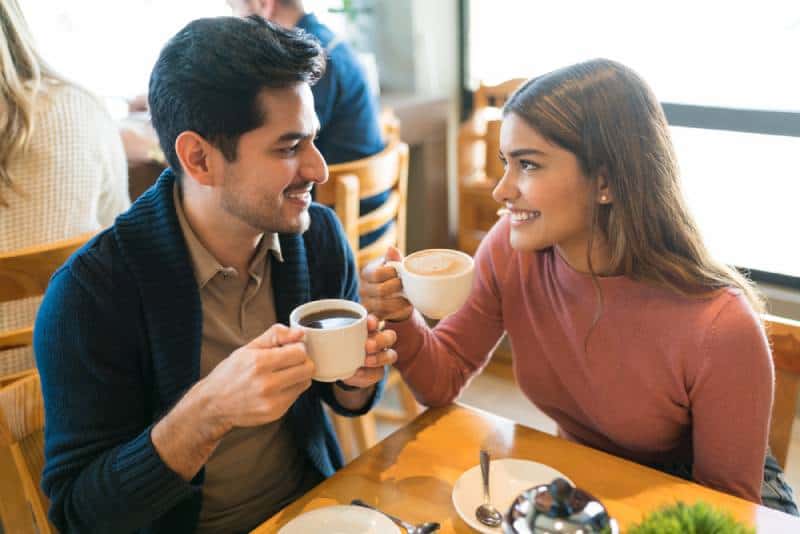 Junge Liebhaber genießen Kaffee, während sie sich in einem Café ansehen