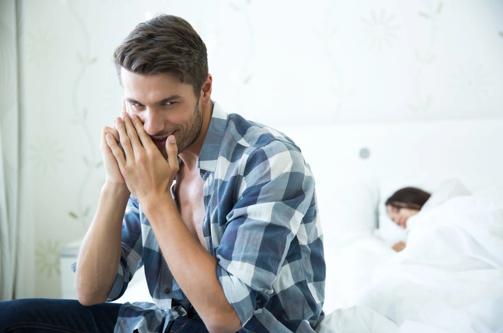 Mann sitzt auf dem Bett