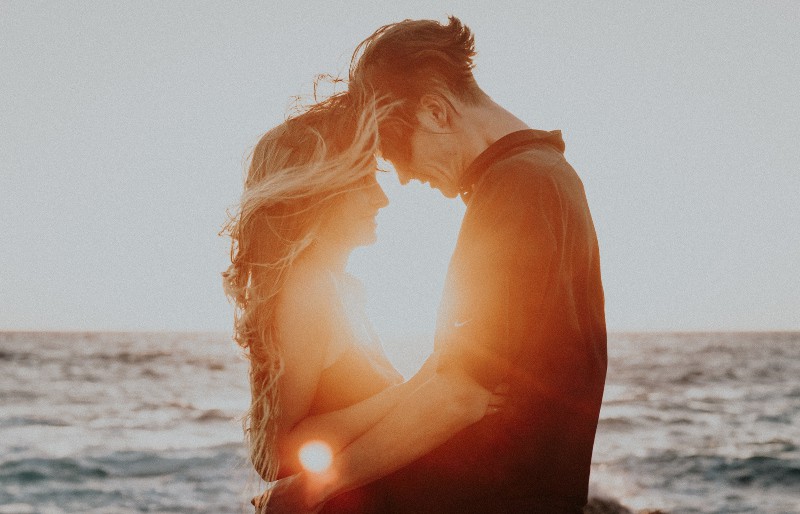 Mann und Frau umarmen nahe Meer während der goldenen Stunde