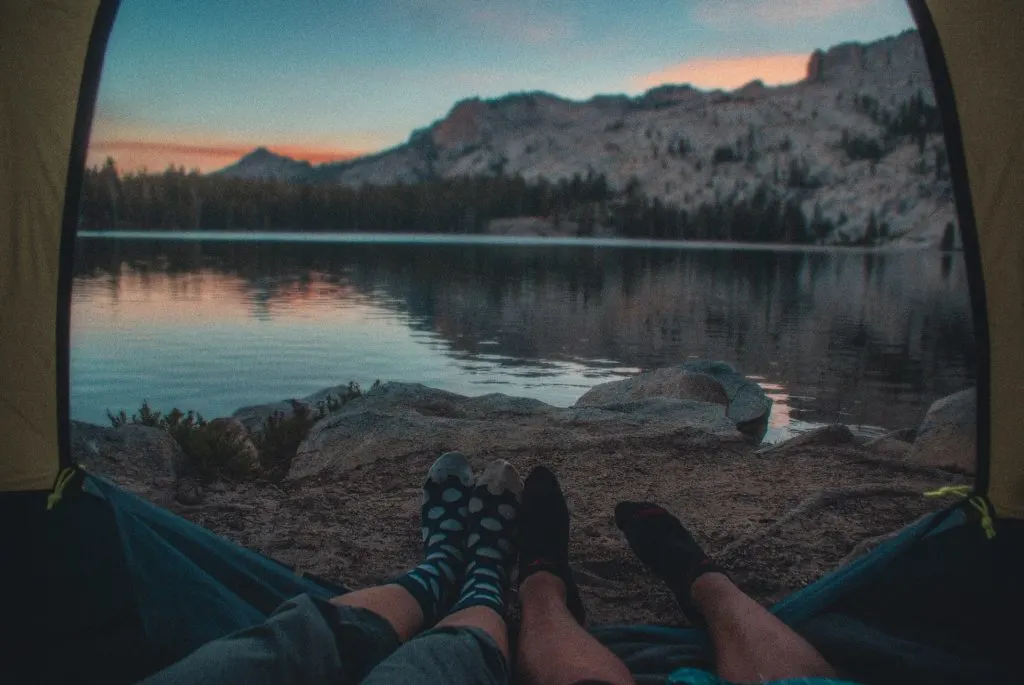 die Beine eines Mannes und einer Frau in einem Zelt an einem Bergsee