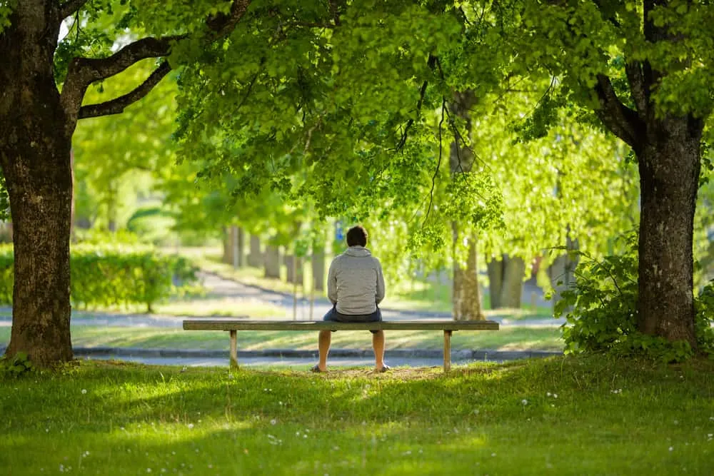 ein Mann, der alleine auf einer Parkbank sitzt