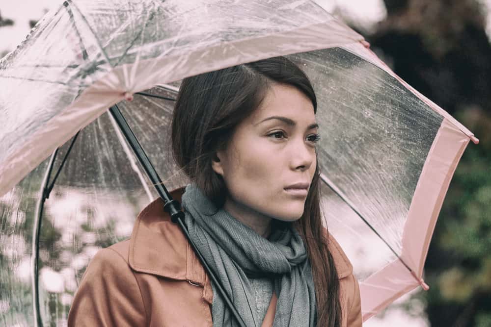 ein Porträt einer traurigen Brünette unter einem Regenschirm