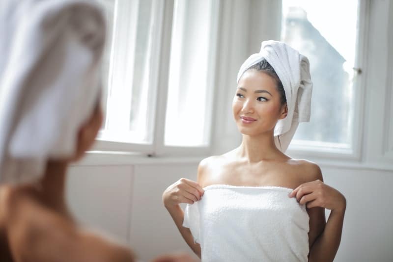 ein Spiegelbild im Spiegel einer lächelnden Frau nach dem Baden