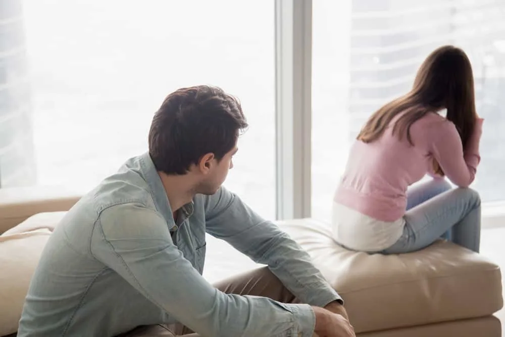 ein junges Paar sitzt nach einem Streit auf der Couch