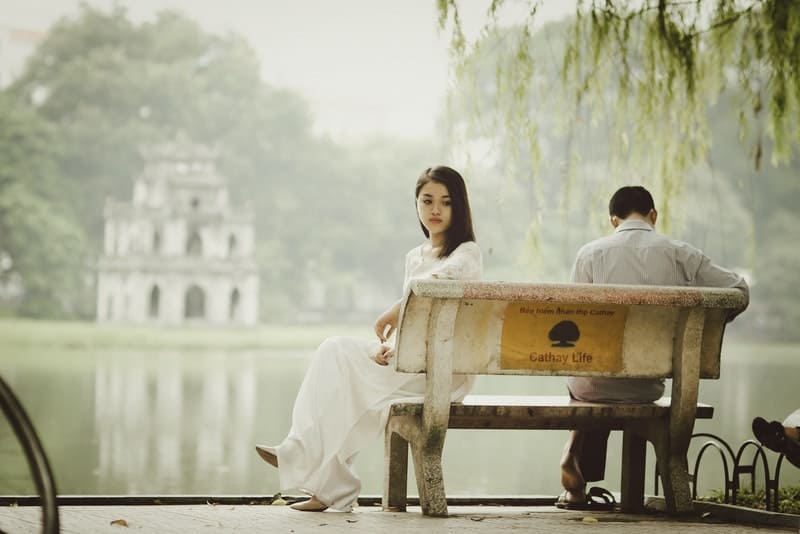 eine traurige Frau, die neben einem Mann auf einer Bank sitzt