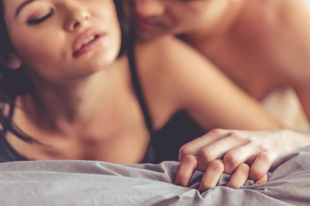 leidenschaftlicher Sex eines liebenden Paares auf einem weißen Laken