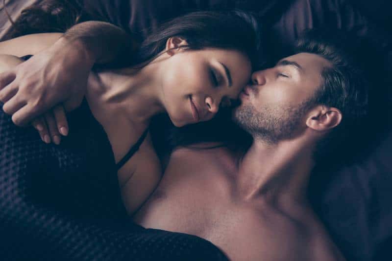 schönes Paar, sie umarmen sich unter der Decke im Bett