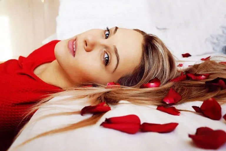 Das Mädchen liegt auf einem Bett mit Rosenblättern