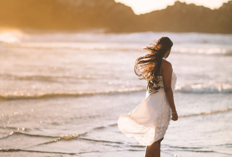 Das Mädchen geht in einem Kleid am Strand entlang