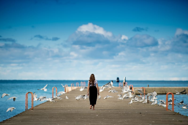 Das Mädchen geht den Holzweg über dem Meer entlang