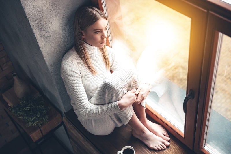 Das Mädchen sitzt am Fenster, während es regnet