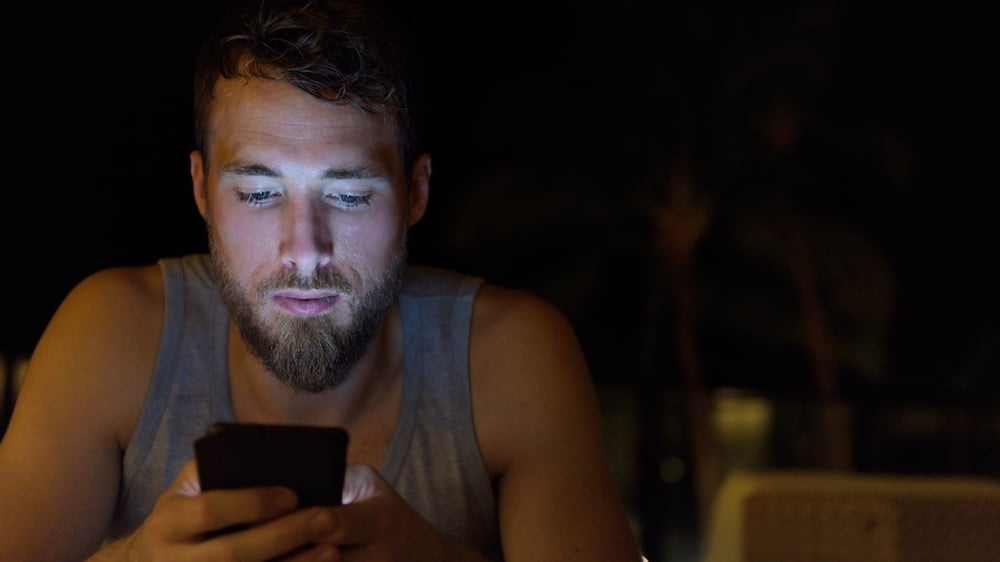 Der Mann im Unterhemd schreibt SMS sorgfältig