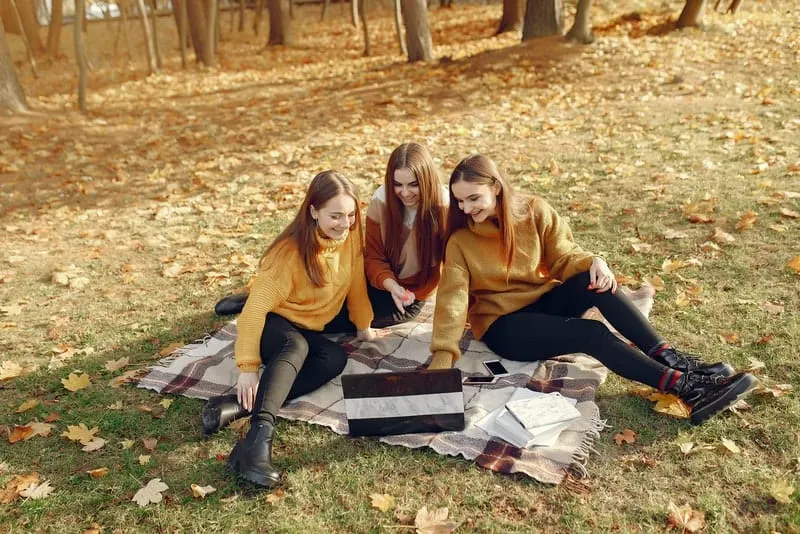 Drei junge Frauen sitzen auf Decken im Park