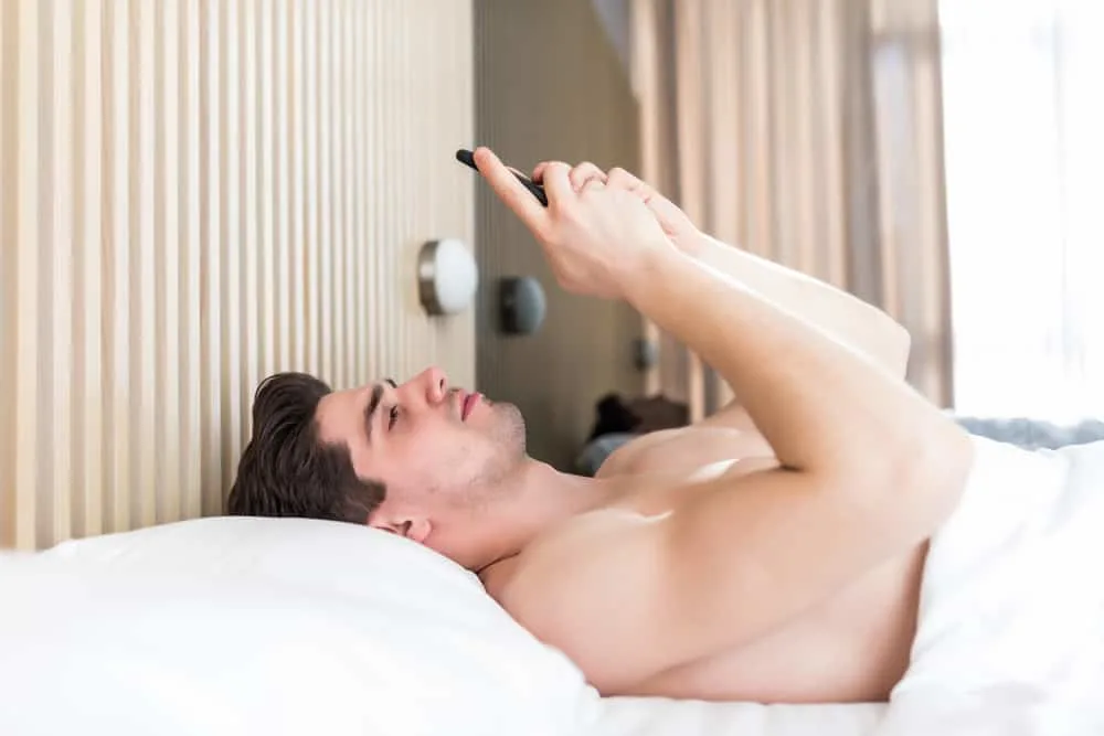 Ein Mann im Bett schreibt morgens eine Nachricht